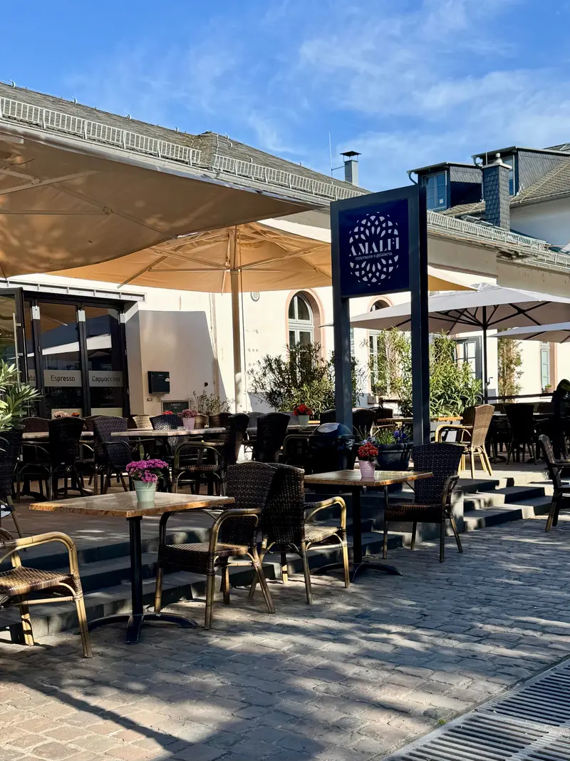 Amalfi Gelateria Terrasse mit Sonnenschirmen und Logo-Stele